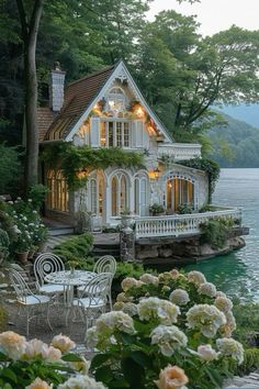 a white house sitting on top of a lush green hillside next to a body of water