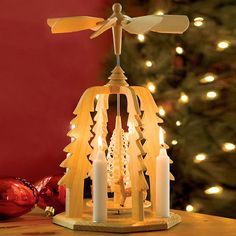 a lighted christmas tree with candles in the shape of a bell and a dragon on top