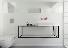 a bathroom with a toilet, sink and mirror above it's countertop area