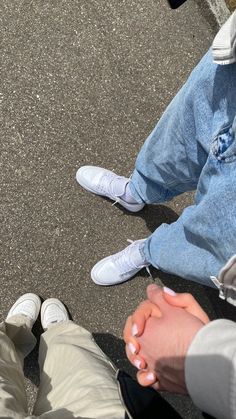 two people holding hands while sitting on the ground