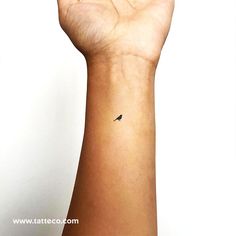 a small black bird tattoo on the left wrist is shown in front of a white background