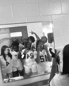 a group of girls standing in front of a mirror