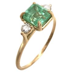 an emerald and diamond ring with two diamonds on the side, set in yellow gold