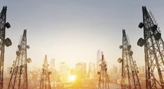 the sun is setting behind several cellular towers in front of a cityscape with skyscrapers