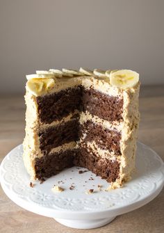 a slice is taken out of the chocolate and banana layer cake on a white plate