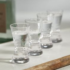 four shot glasses lined up on a table with a wooden stick in front of them