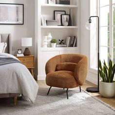 a bed room with a neatly made bed and a chair in front of a window