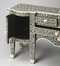 an ornate black and white table with drawers on it's sides, one drawer open