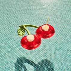 two red candles sitting on top of a blue swimming pool