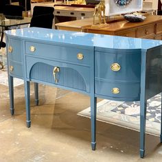 a blue table with two drawers and gold pulls on it in a room filled with furniture