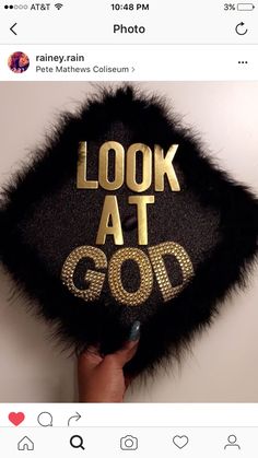 someone holding up a fake graduation cap with the words look at god on it