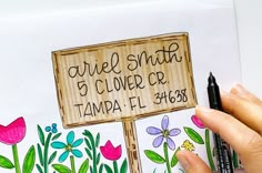 a hand holding a marker next to a drawing of flowers and a sign that says, currie smith 5 clover cr tampa fl 340