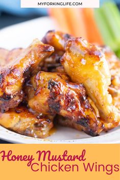 chicken wings covered in bbq sauce on a plate with celery and carrots