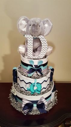 a diaper cake that has an elephant on top and blue ribbon around the bottom