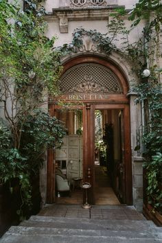 a man standing in the doorway of a building with plants growing on it's sides