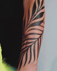 a black and white palm leaf tattoo on the arm