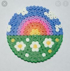 a small plastic doily with flowers and a rainbow in the middle on a white surface