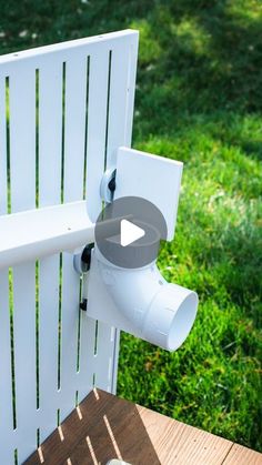 a white chair sitting on top of a wooden table in the grass next to a cup