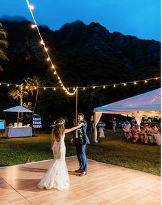 a bride and groom dance on the dance floor at their wedding reception in front of mountains