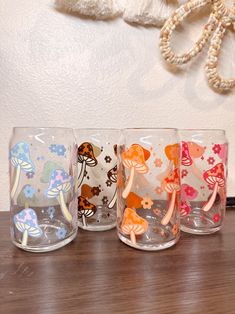 four glasses with different designs on them sitting on a table next to a stuffed animal