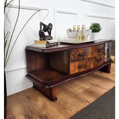 a wooden dresser sitting on top of a hard wood floor next to a potted plant