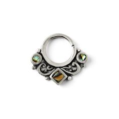 a silver colored nose ring with green and yellow stones on the inside, surrounded by filigrees