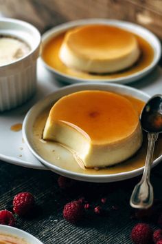 two plates with pancakes and raspberries on them, one has a spoon in it