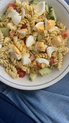 a white bowl filled with pasta and veggies on top of a blue cloth