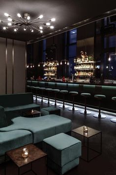 a dimly lit bar with blue couches and stools