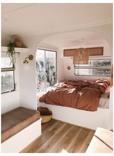 a bedroom with a bed, window and bench in the corner next to a window