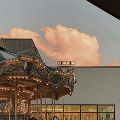 a merry go round in front of a building with lights on it's sides