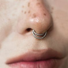 a woman's nose with an open nose ring on top of her nose,