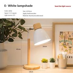 a white lamp sitting on top of a wooden table next to a potted plant