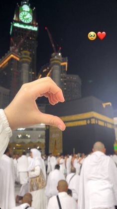 a person holding out their hand in the middle of a large group of people with buildings in the background