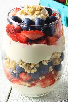 a dessert in a glass with strawberries, blueberries, and other fruit on top