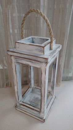 an old white wooden lantern with rope handle