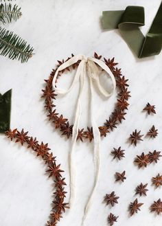 an assortment of christmas decorations on a white table with greenery and ribbon tied around it