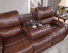 a brown leather reclining couch sitting in a living room next to a coffee table