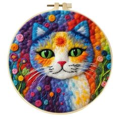 a multicolored cat with green eyes is shown in this hand embroidered art piece