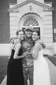 two women and a man are posing for a photo in front of a building