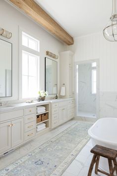 a large bathroom with white cabinets and marble counter tops, along with a tub in the middle