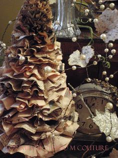 a christmas tree made out of old books and other items is displayed in front of a clock