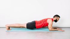 a man is doing push ups on a blue mat in front of a white wall