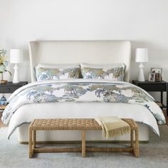 a large bed sitting under a wooden ceiling next to a night stand with two lamps on top of it