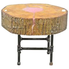 a wooden table with metal legs and a pink flower on the top, against a white background