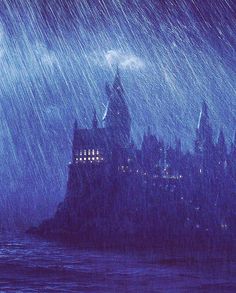 an image of a castle in the rain at night with lights on and water splashing around it