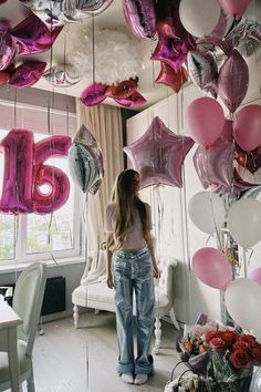 a woman standing in front of balloons that spell out the number sixteen, surrounded by pink and white balloons