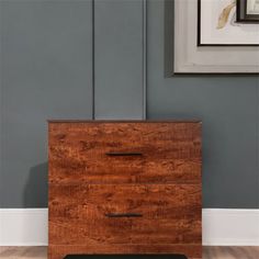 a wooden dresser sitting on top of a hard wood floor next to a framed picture