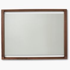 a wooden framed mirror on a white wall with clippings to the bottom half