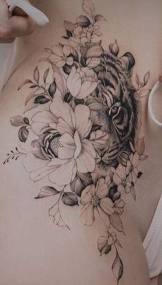 a woman's stomach with flowers and a tiger tattoo on the side ribcage